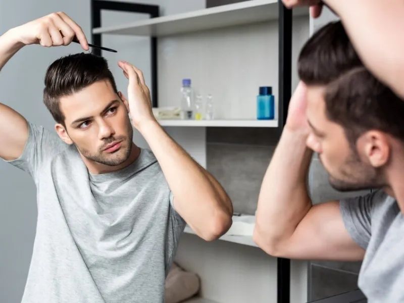 “Man applying leave in conditioner to long curly hair”