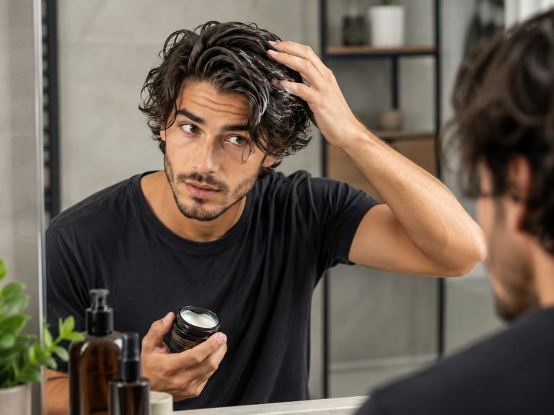 Man styling medium wavy hair using lightweight hair cream